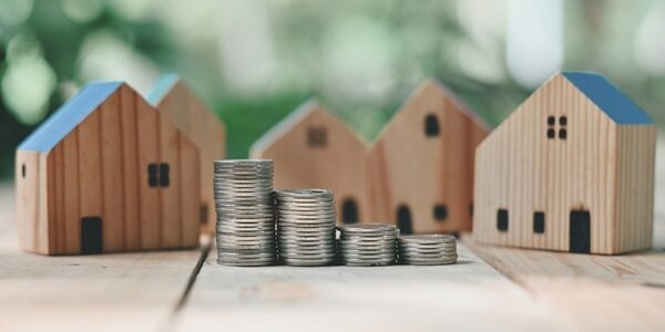 Close,Up,Stack,Of,Coin,And,Toy,Wooden,House,On
