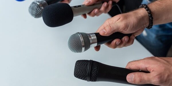 Close-up,Of,Four,Hands,Holding,Different,Microphones,,Suggesting,A,Press